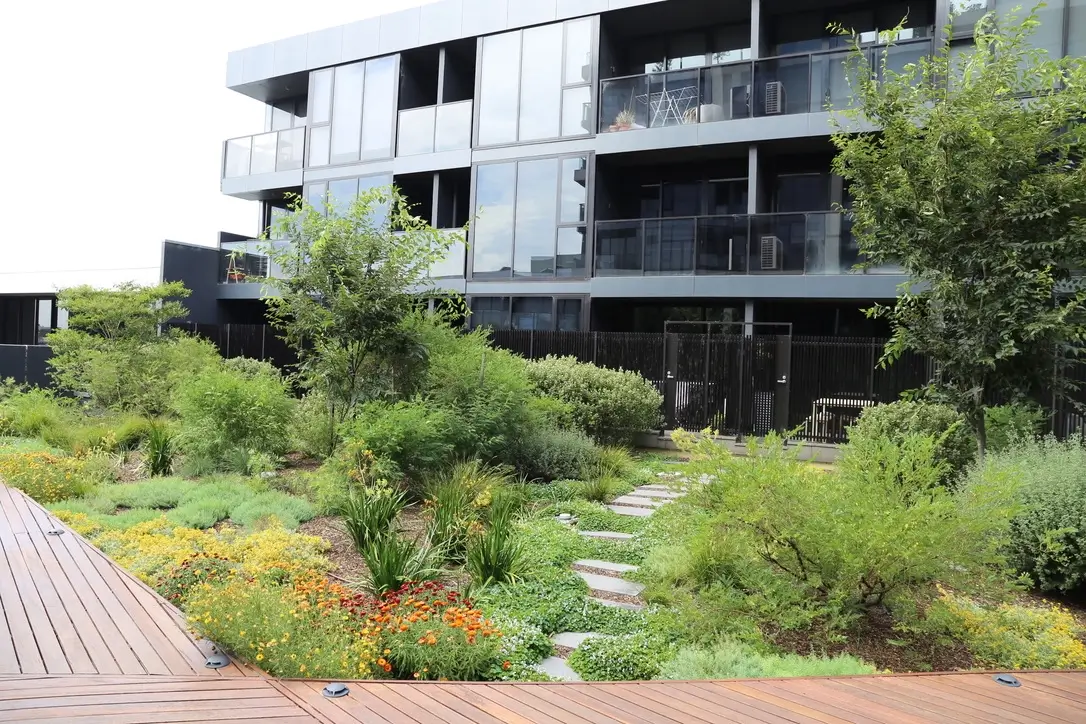 Modern apartment building with lush green garden and wooden deck