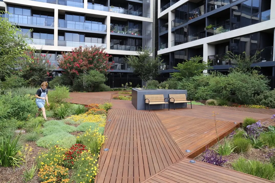 Modern apartment complex with wooden deck and colorful garden landscaping