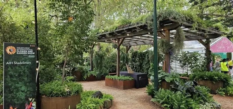 Wooden pergola with lush plants and garden display at flower show