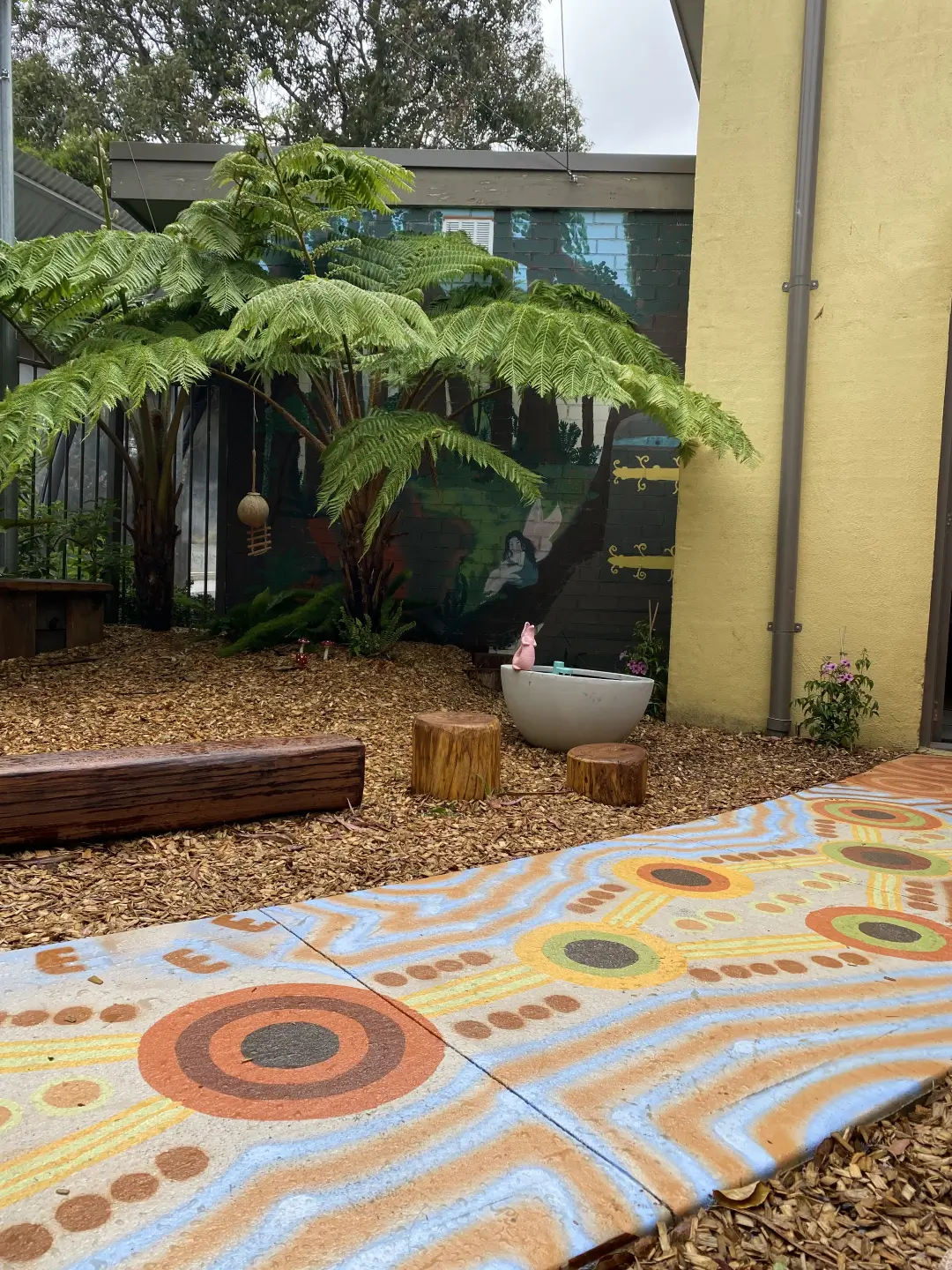 Tree fern garden with colorful tile floor and wooden stumps