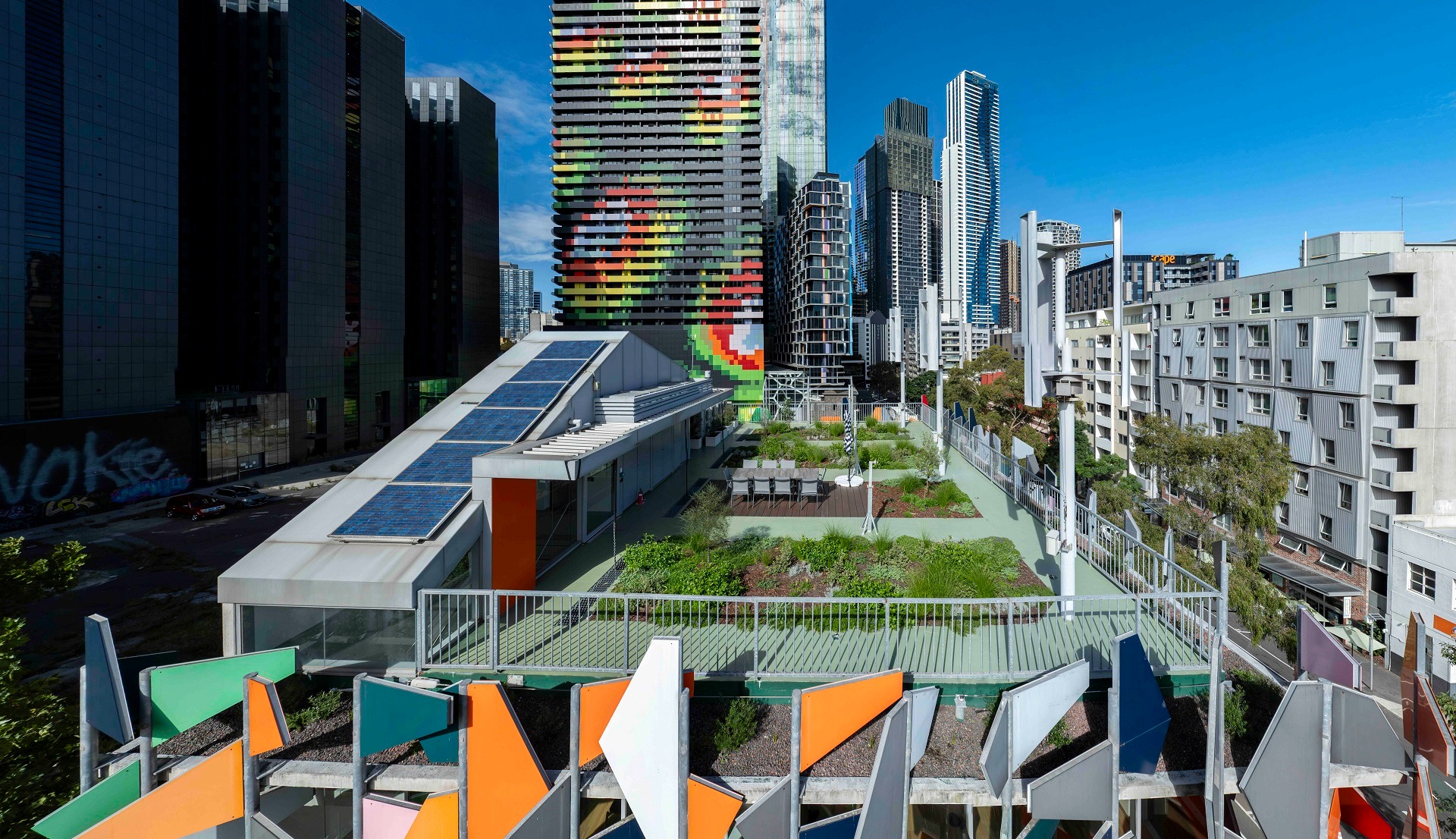 Aerial view of a living roof in Carlton, Melbourne, featuring native plantings, solar panels, and a colourful façade, demonstrating the benefits of a living roof in dense urban settings.