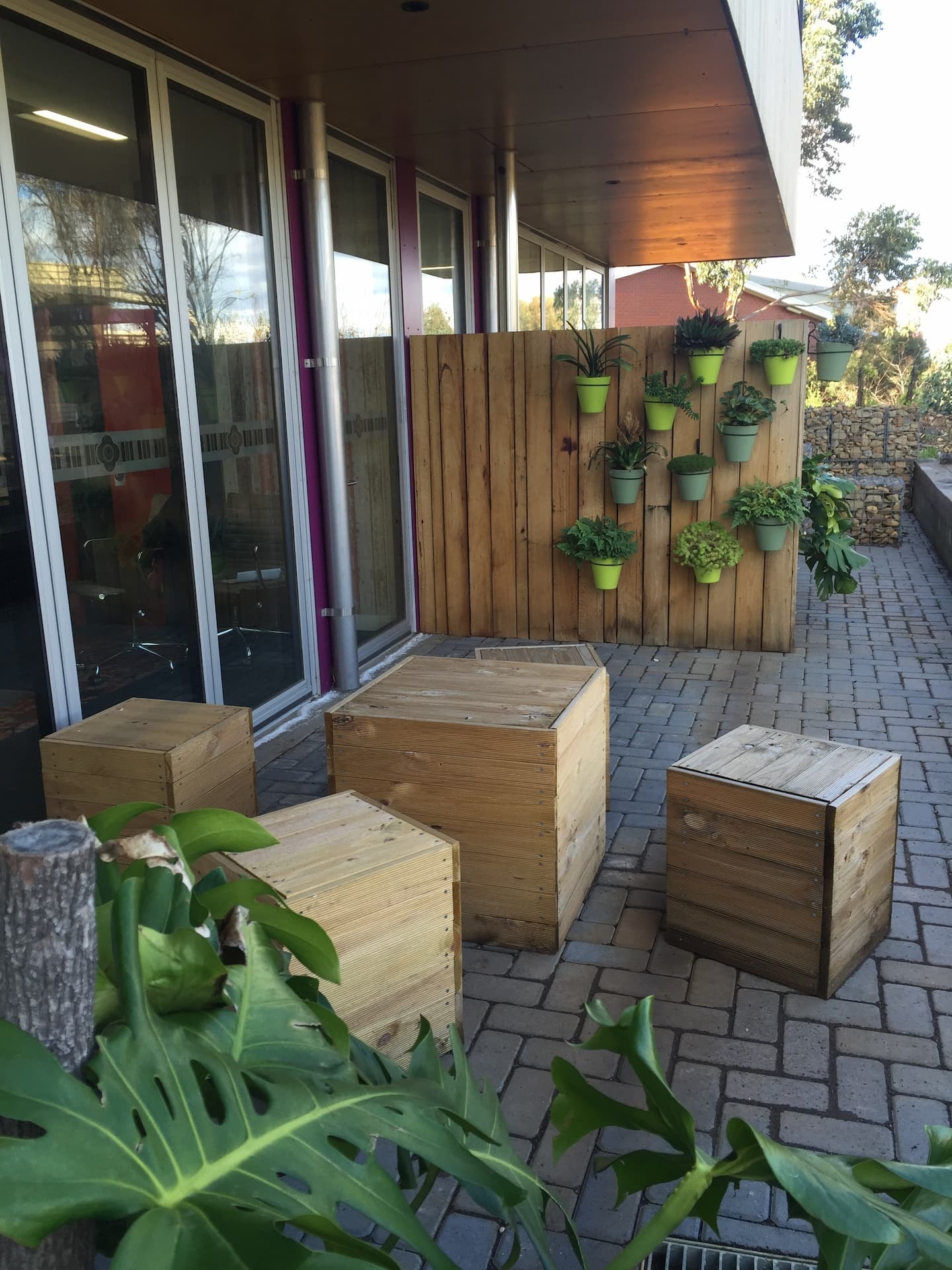 Permeable paving patio with wooden cube seating and a vertical planter wall.