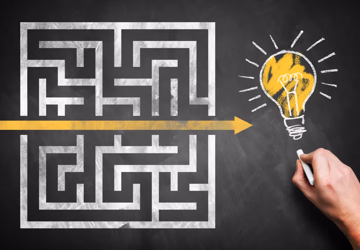 A hand drawing a chalk maze on a blackboard, with an arrow bypassing the maze leading directly to a light bulb symbolizing a bright idea or solution.