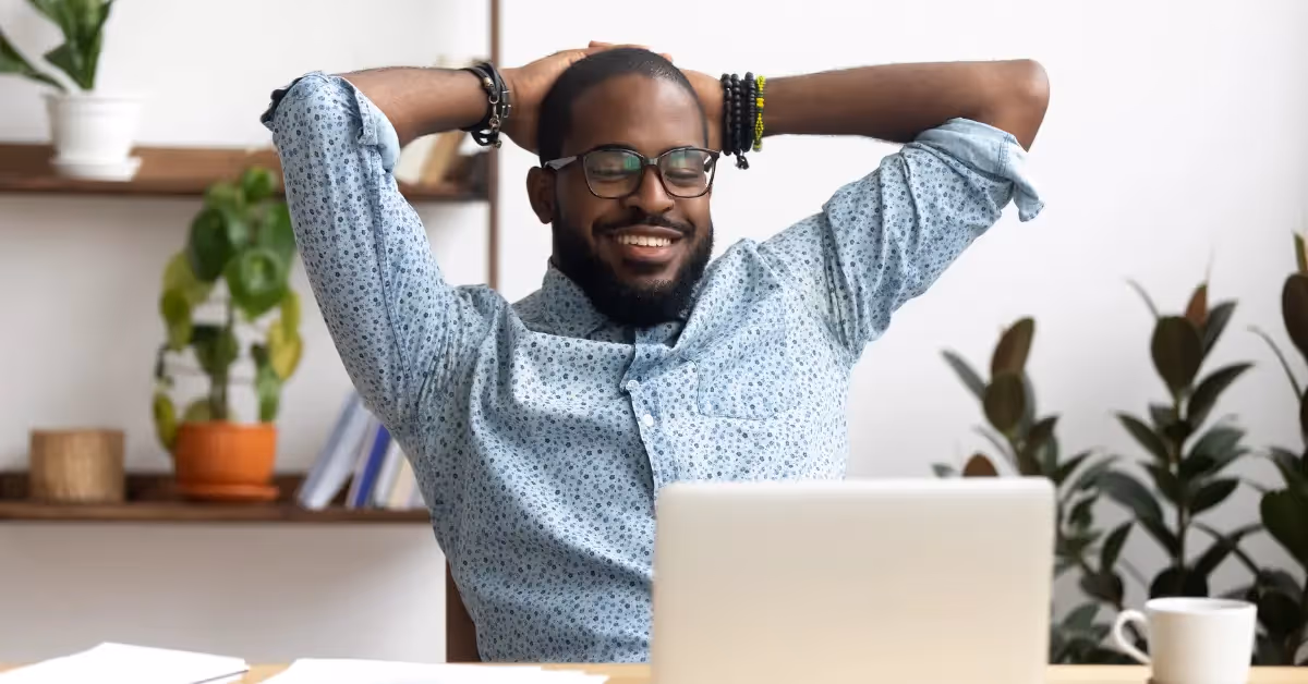 smiling accountant sitting back on his chair looking at his laptop