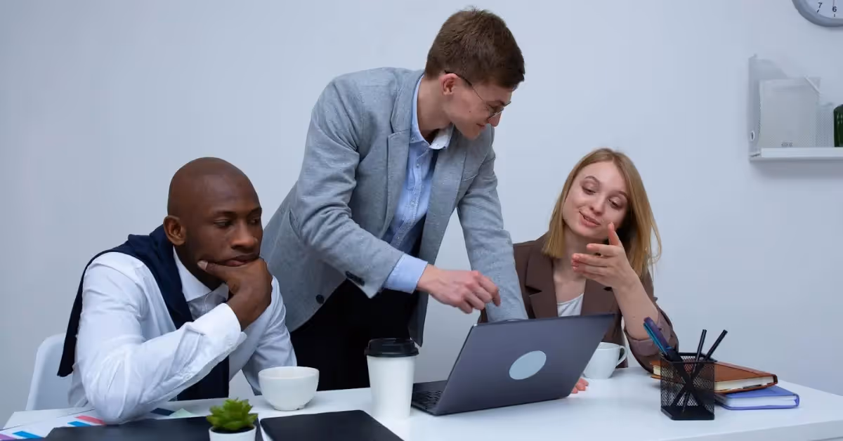 Three colleagues looking at a laptop and discussing their work 