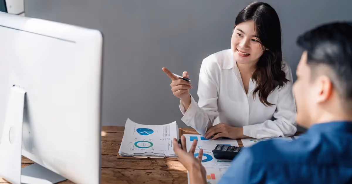 Two accountants discussing financials and looking at reports on a computer