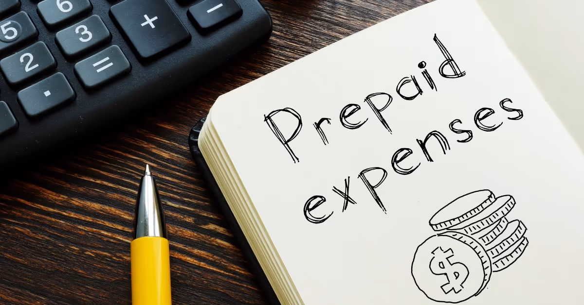 A notebook with the words "prepaid expenses" and a drawing of coins