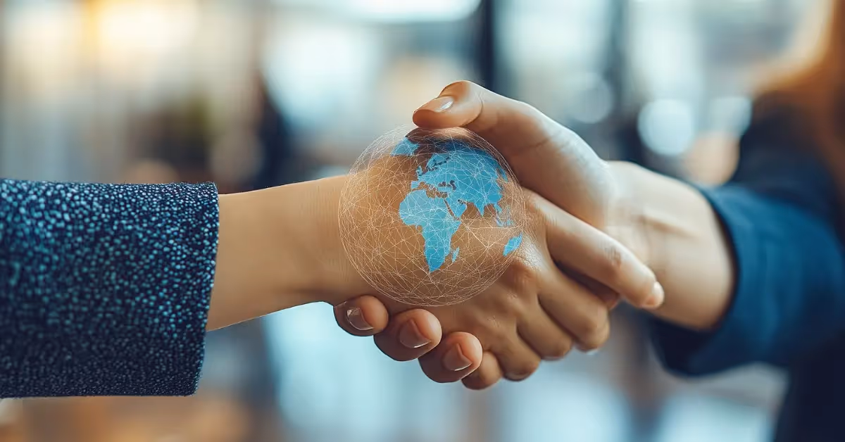 Business people shaking hands overlaid with a graphic of a world map