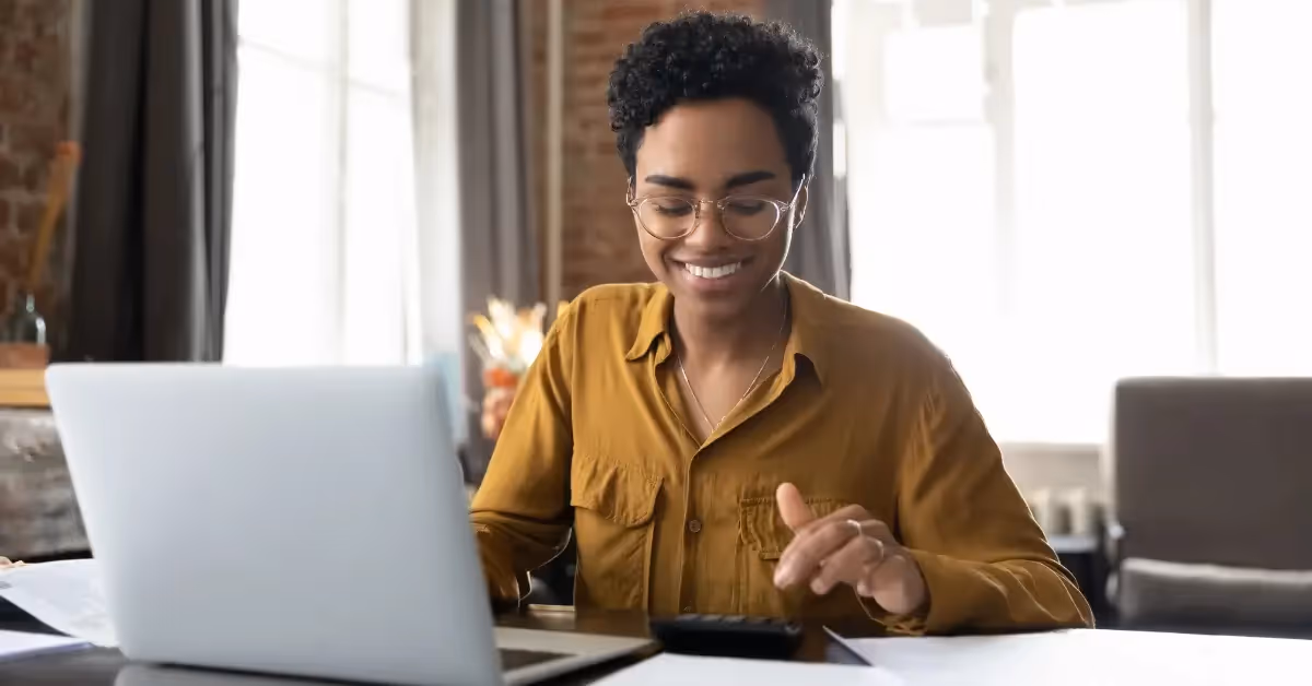 A smiling accountant working on her laptop and calculator