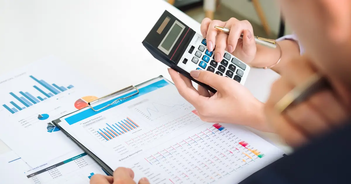 Two staff accountants reviewing intercompany reports with a calculator during a multi-entity month-end close