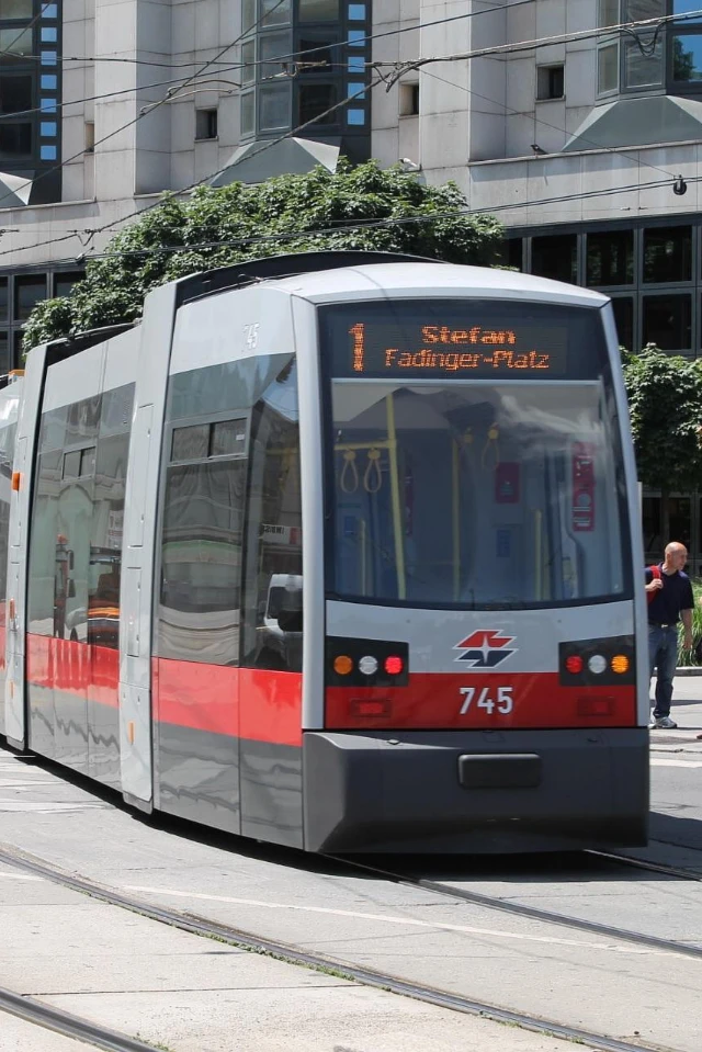 Städtische Straßenbahn der Linie 1 mit Zielanzeige Stefan-Fadinger-Platz, fährt auf Schienen in der Innenstadt.