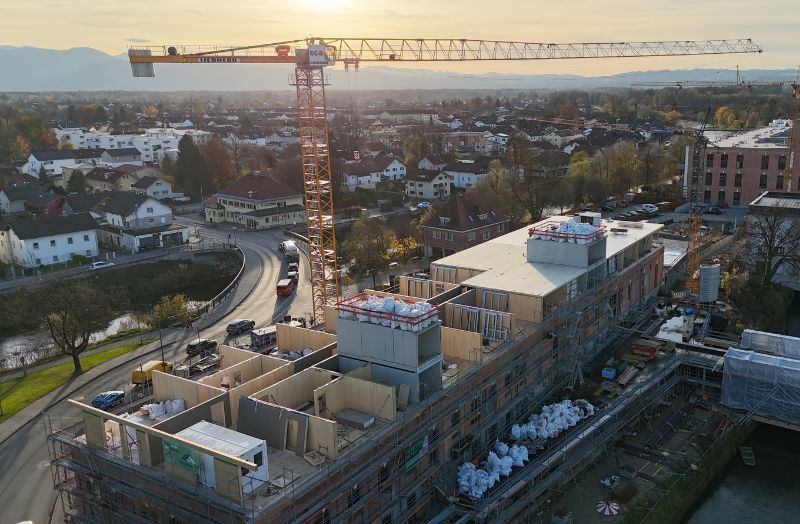 Luftaufnahme einer Holzbau-Baustelle mit Kran und mehrgeschossigem Gebäude im Bau – moderner Holzbau im urbanen Wohnbau mit effizienter Baustellenlogistik.