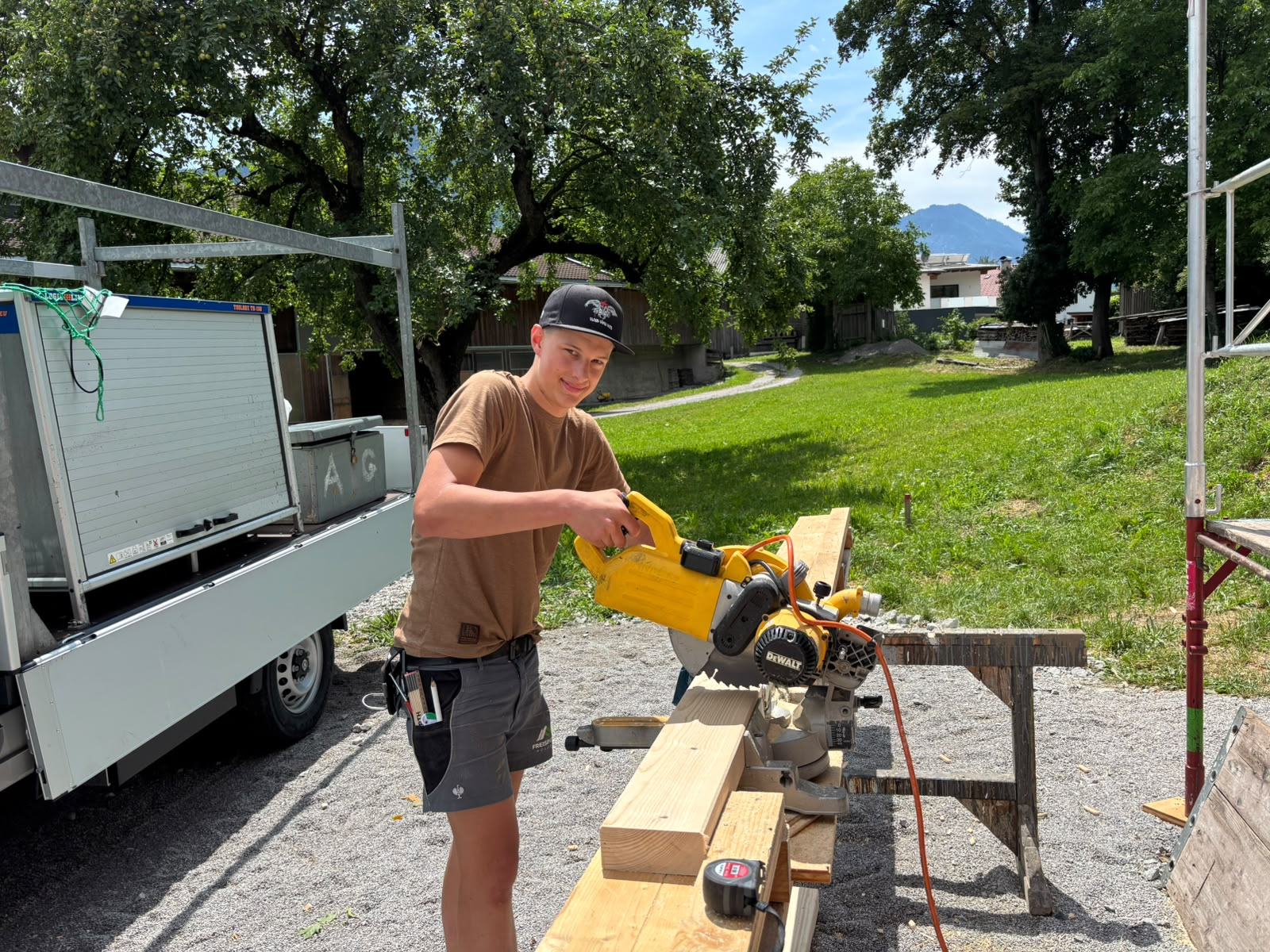 Junger Zimmerer bei Freisinger Holzbau beim Zuschneiden von Holz auf einer Baustelle – Karriere und Zimmererlehre im Holzbau in Tirol.