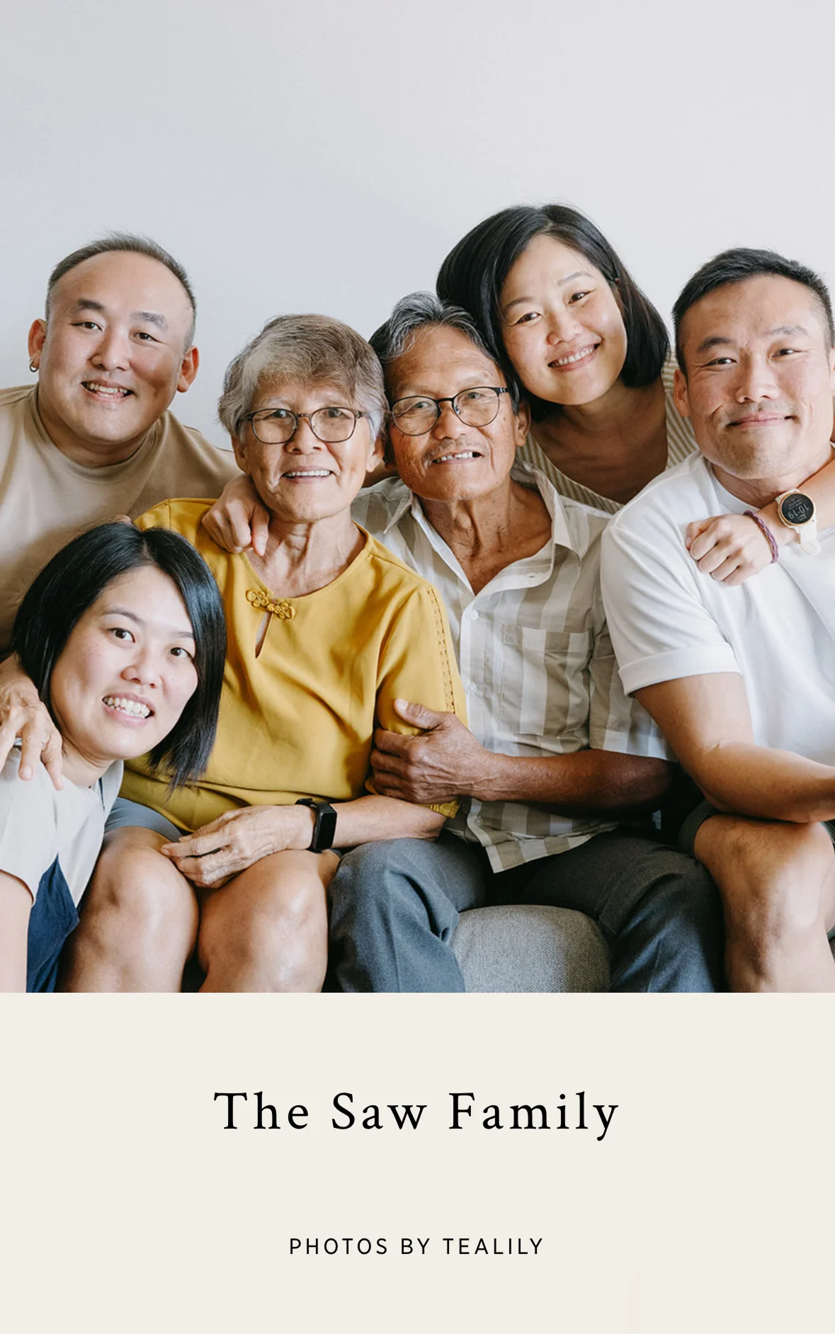 Candid family portrait of six relatives sitting closely on a couch, smiling and embracing in a bright, homey space. Photo by Lulan.
