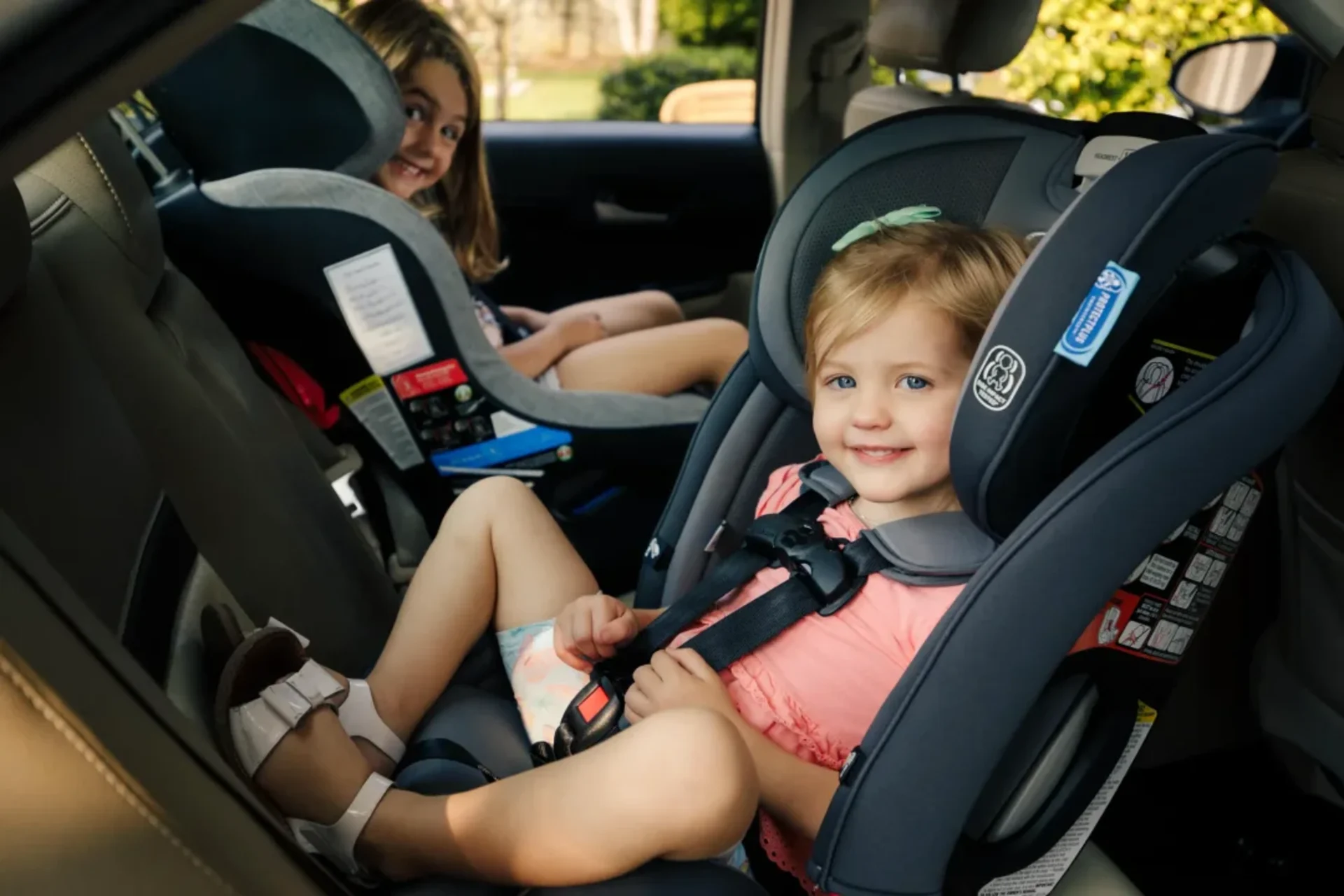 Two children smiling while safely secured in car seats