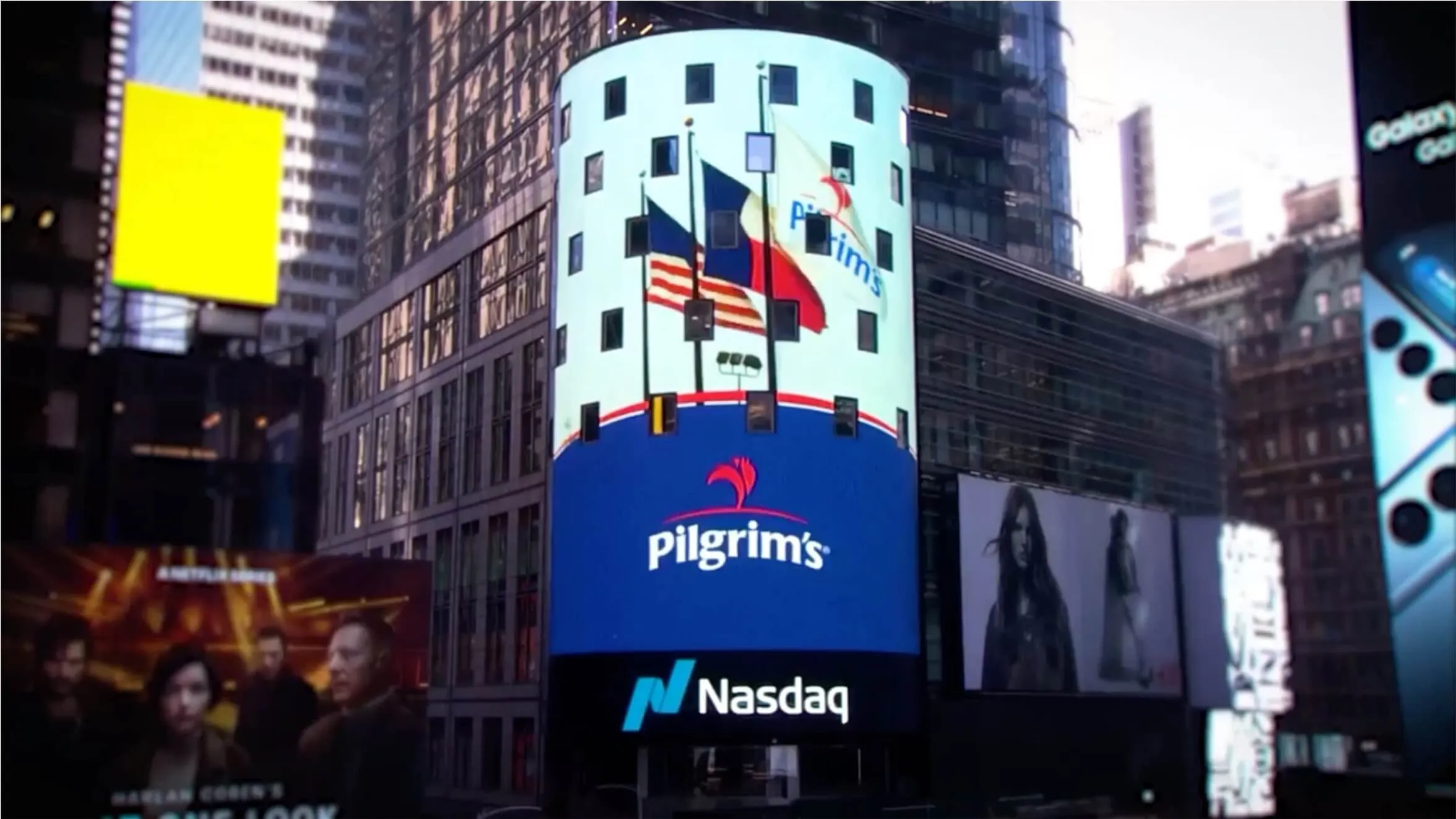 A large digital billboard in Times Square displays the Pilgrims logo above the Nasdaq sign, with American flags and tall buildings in the background.
