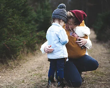 A mother with her baby and reassuring her elder child