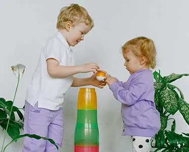 A young child helping another young child play