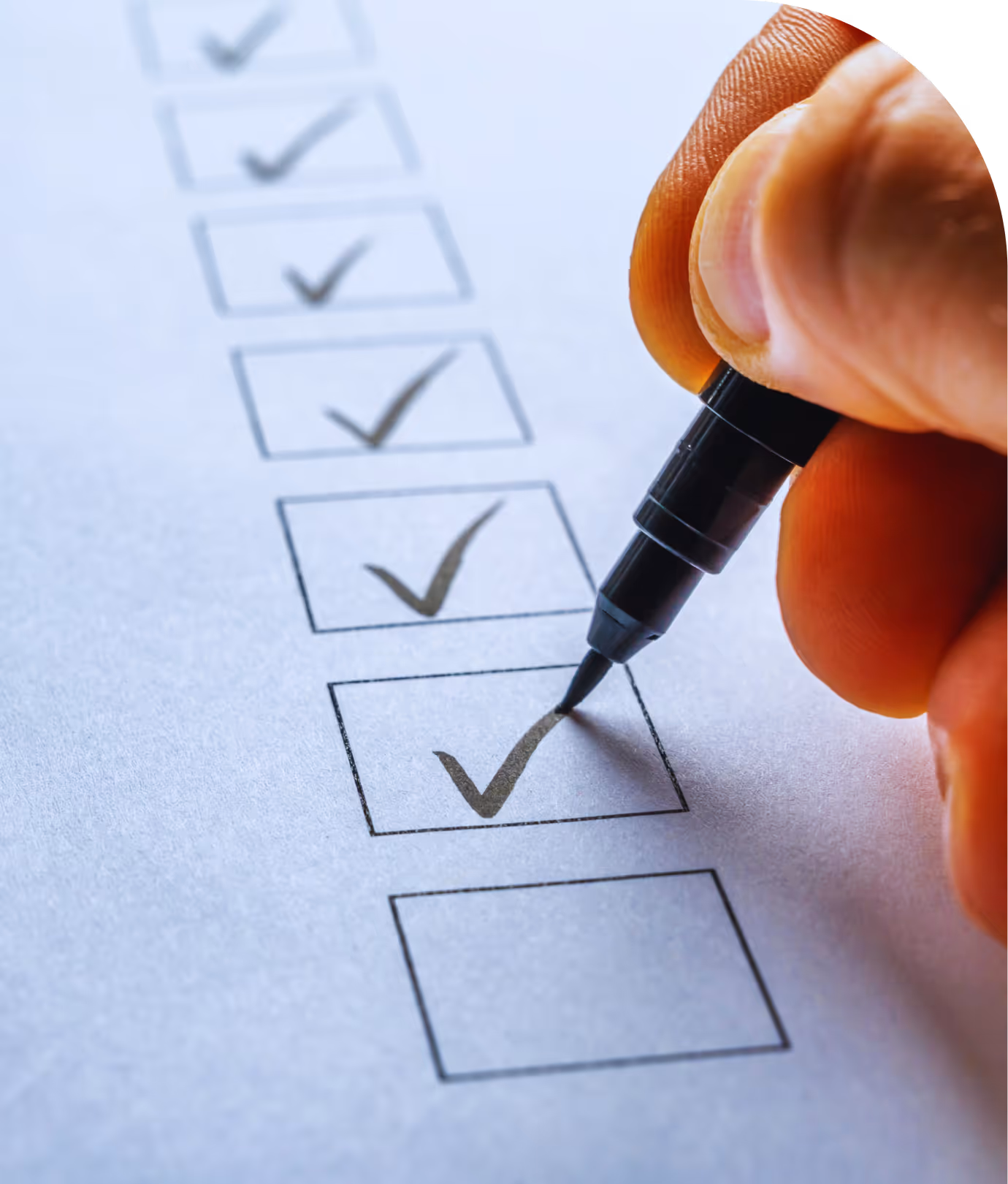 Close-up of a hand marking checkboxes with a pen.