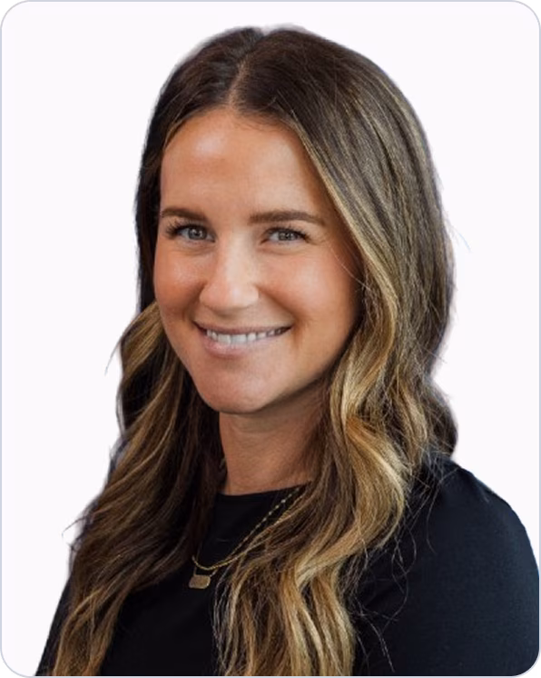 Smiling woman with long wavy brown and blonde hair wearing a black top and a gold necklace.