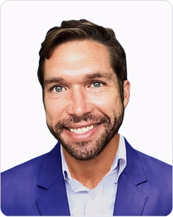 Smiling man with light eyes, short brown hair, and a trimmed beard wearing a blue blazer and white shirt.