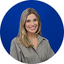Smiling woman with blonde hair wearing a checkered blouse against a blue background.
