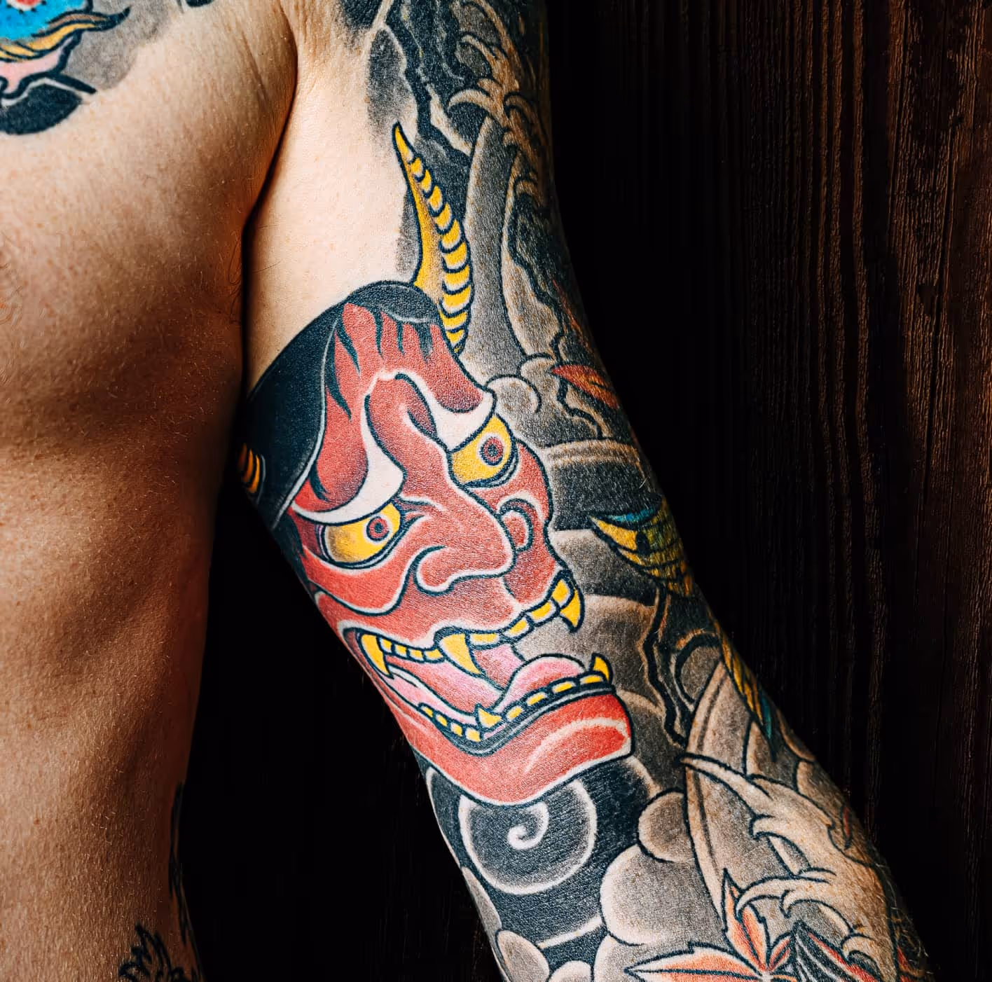Japanese hannya mask tattoo in red, yellow, and black on arm