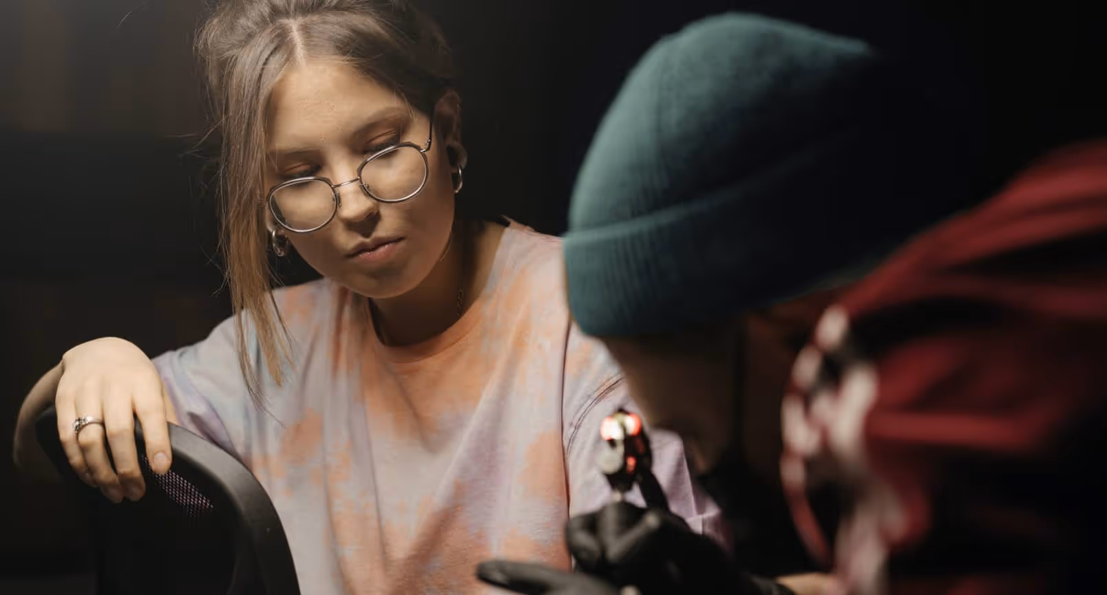 Tattoo artist with glasses working carefully on a client's tattoo
