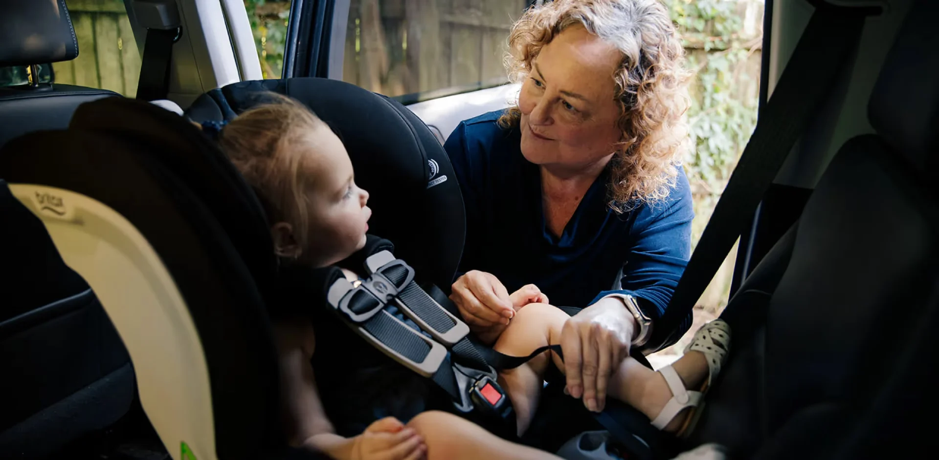 A woman holding a baby in a car seat