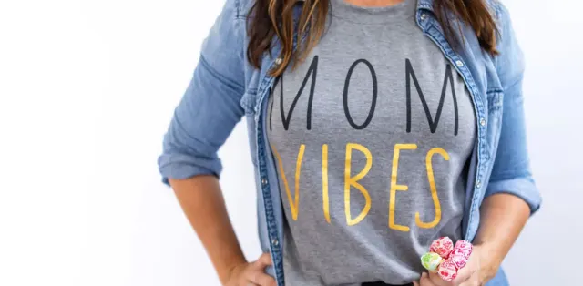 A woman wearing a mom vibes shirt holding a candy