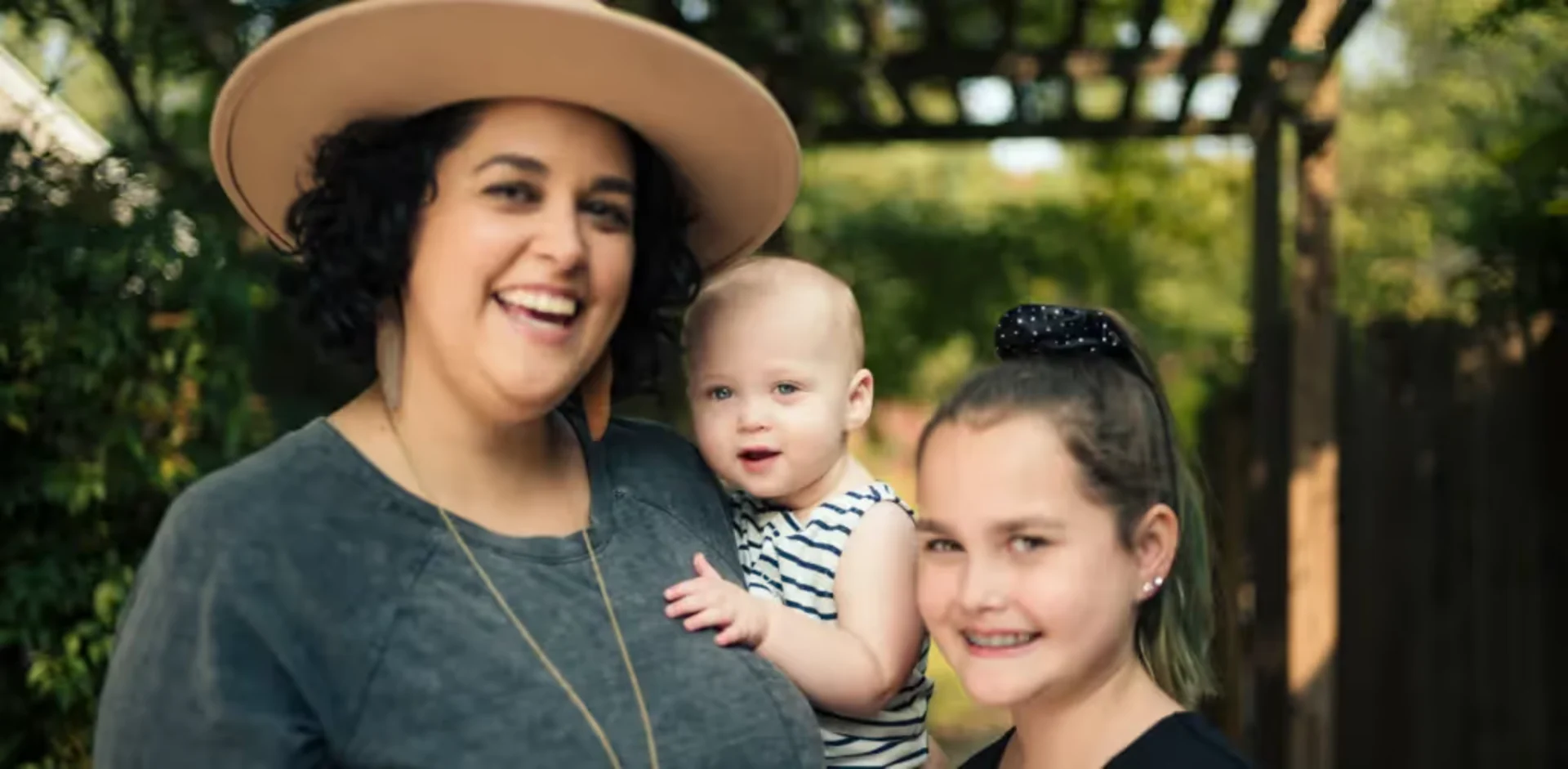 A woman holding a baby and smiling at the camera