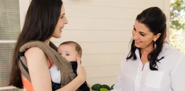 A woman holding a baby in a baby carrier