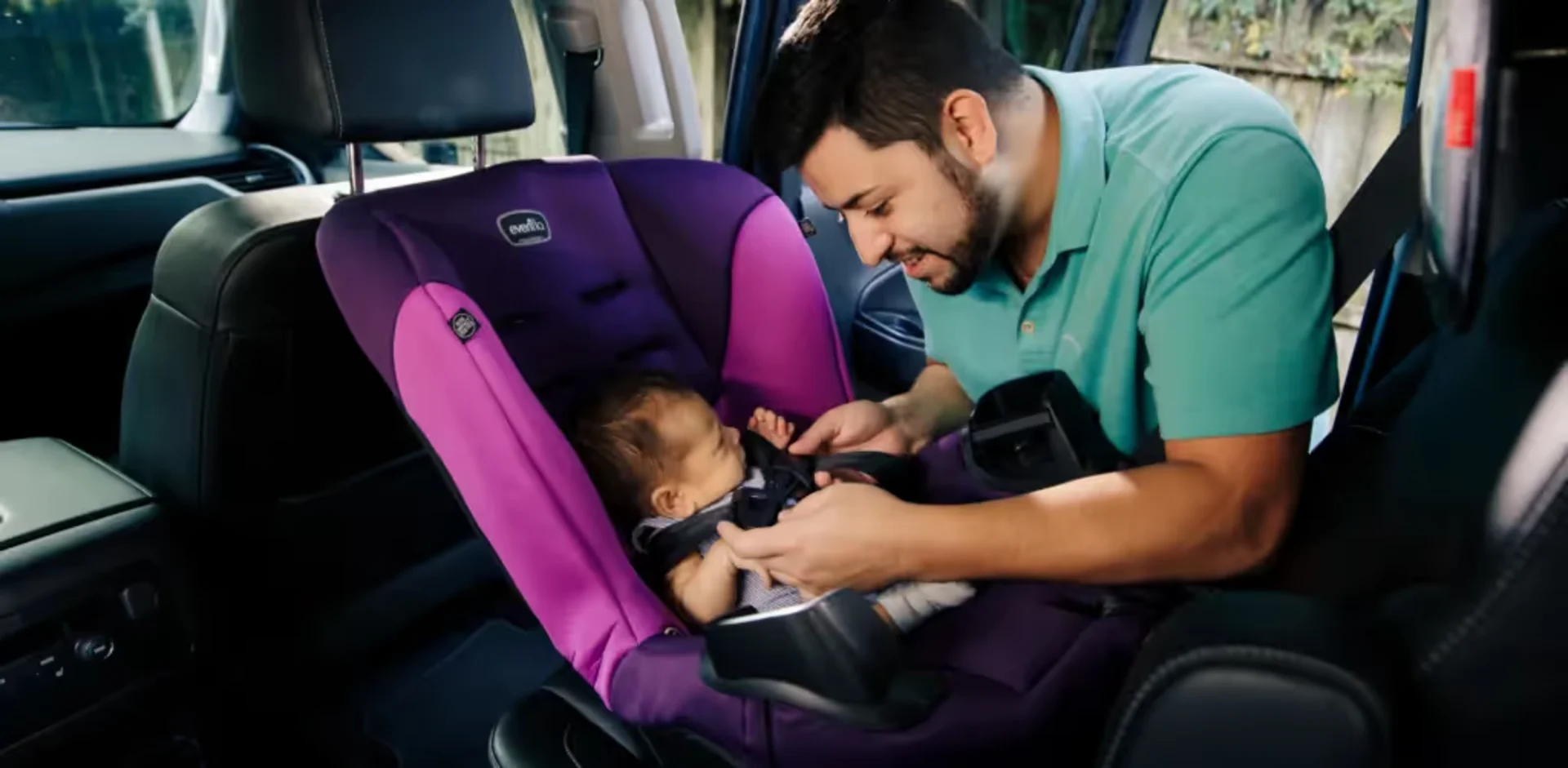 A man holding a baby in a car seat