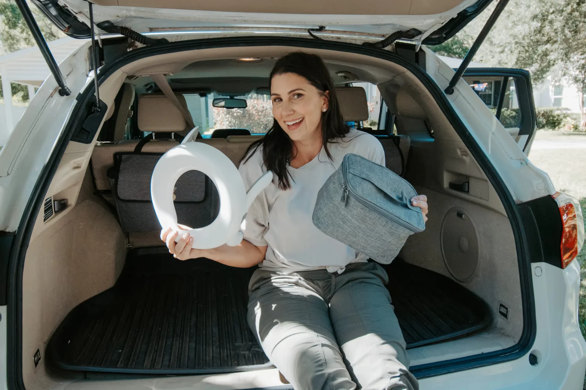 A woman sitting in the back of a car holding a potty