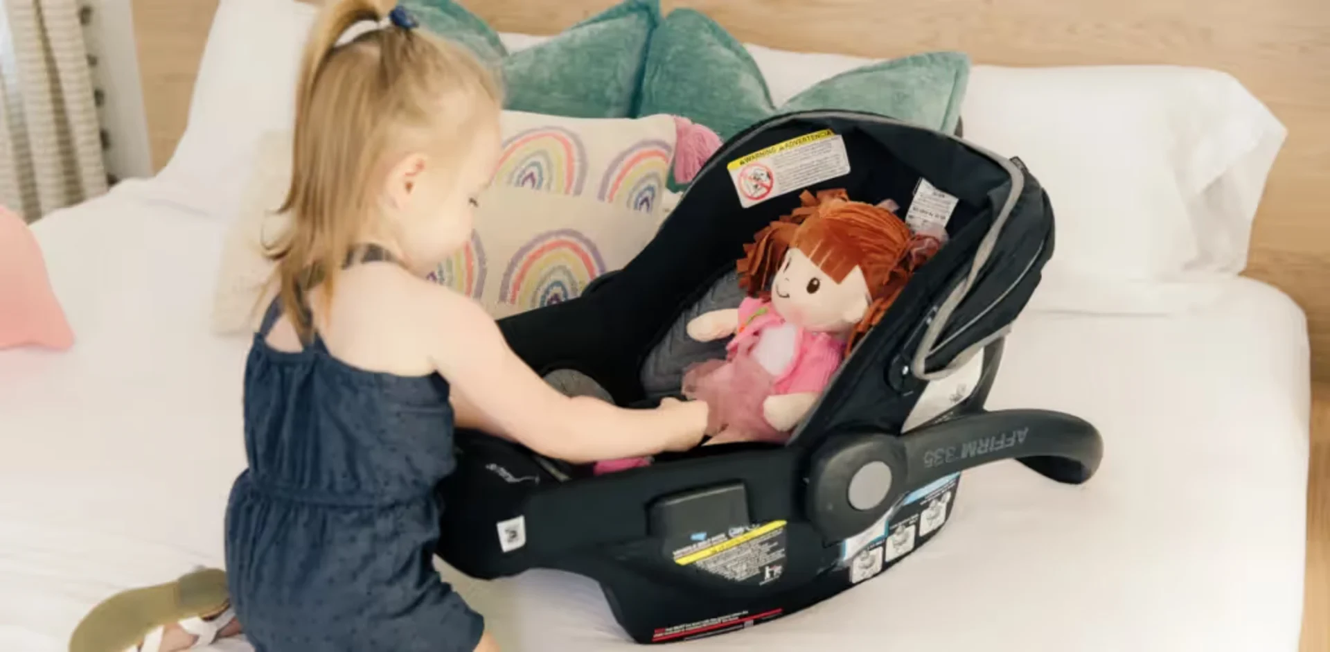 A little girl playing with a doll in a car seat