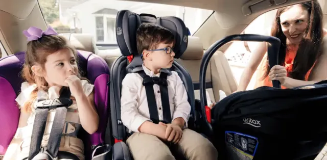 A woman sitting next to a child in a car seat