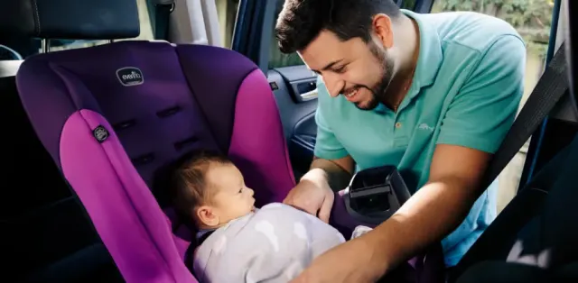 A man holding a baby in a car seat