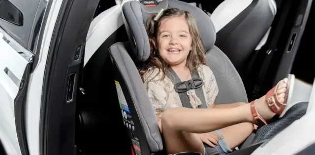A little girl sitting in a car seat smiling