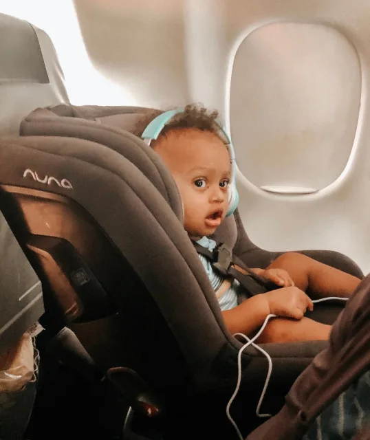 A baby in a car seat with headphones on