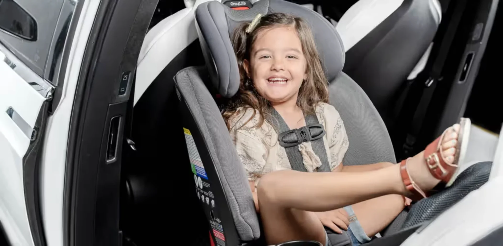 A little girl sitting in a car seat smiling