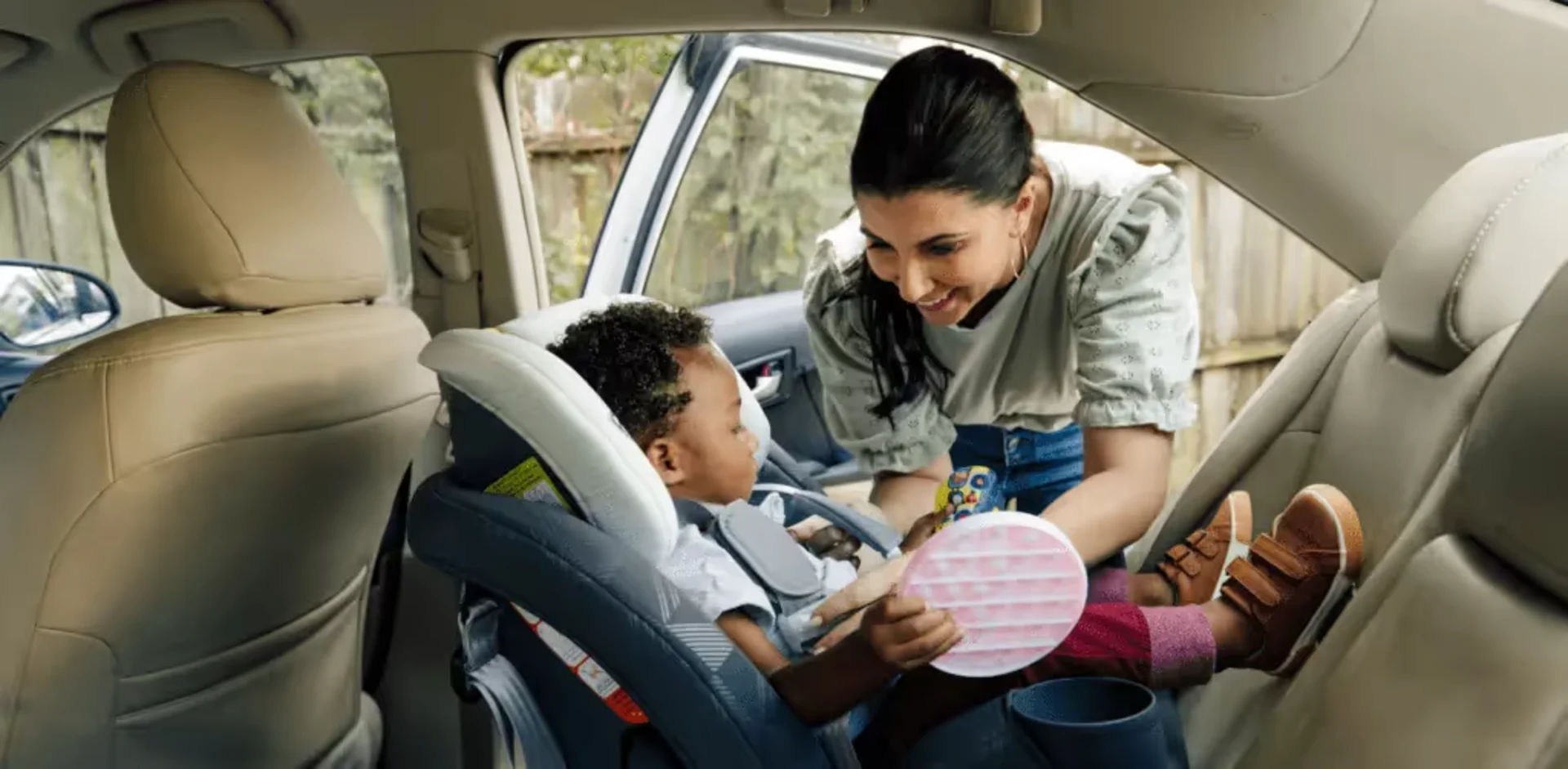 A woman helping a child sit in a car seat