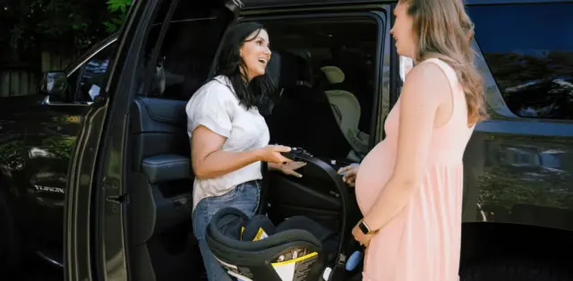 A woman in a pink dress is talking to a woman in a white shirt