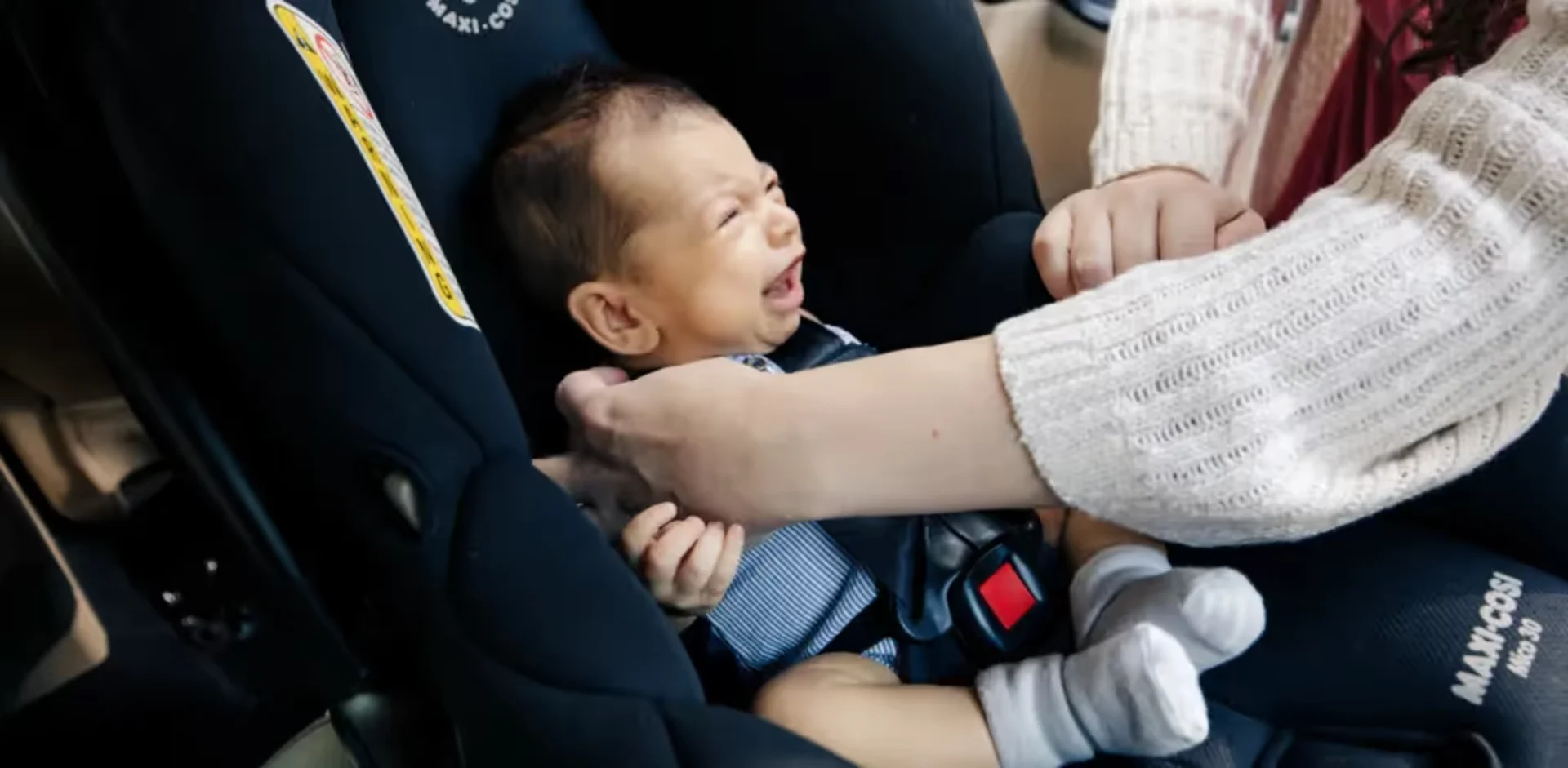 A woman holding a baby in a car seat