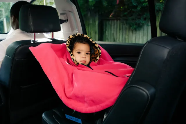 A little girl sitting in the back seat of a car