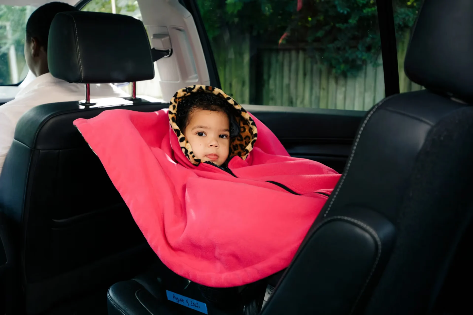 A little girl sitting in the back seat of a car