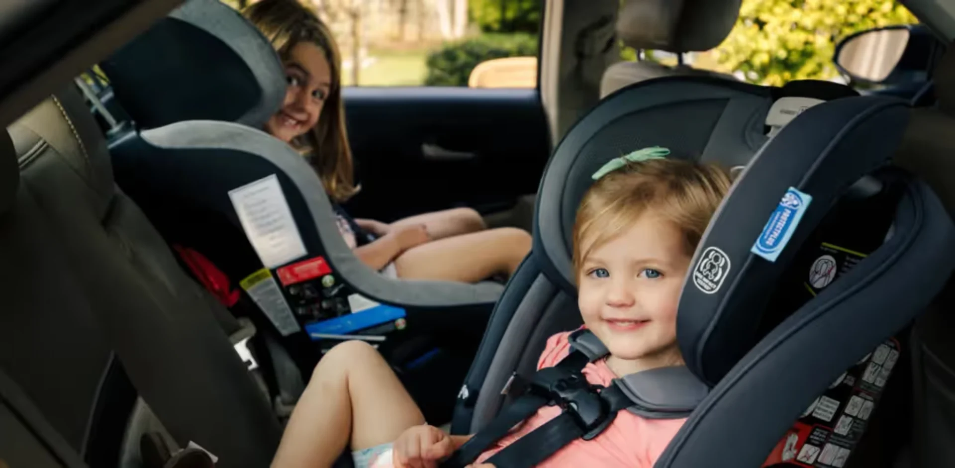 A little girl sitting in a car seat next to a woman