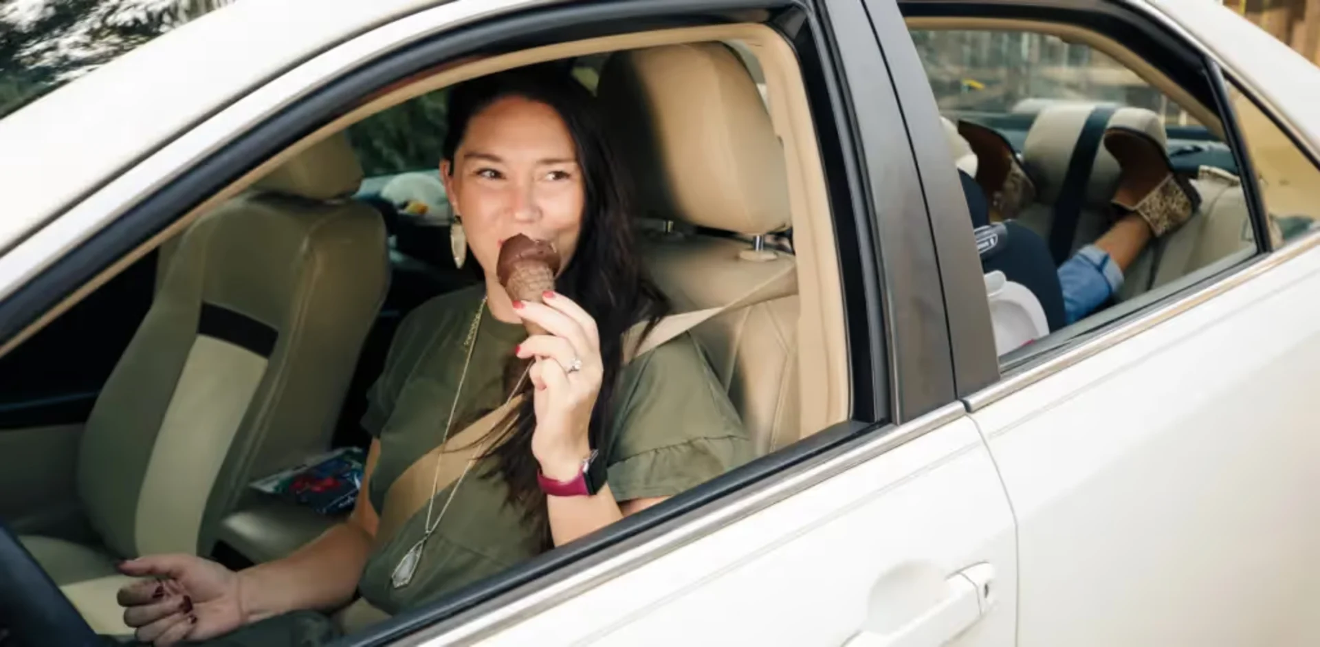 A woman sitting in a car eating
