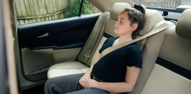A kid sitting in the back seat of a car