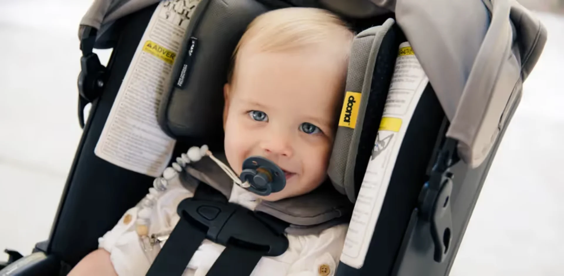 A baby in a stroller with a pacifier in his mouth