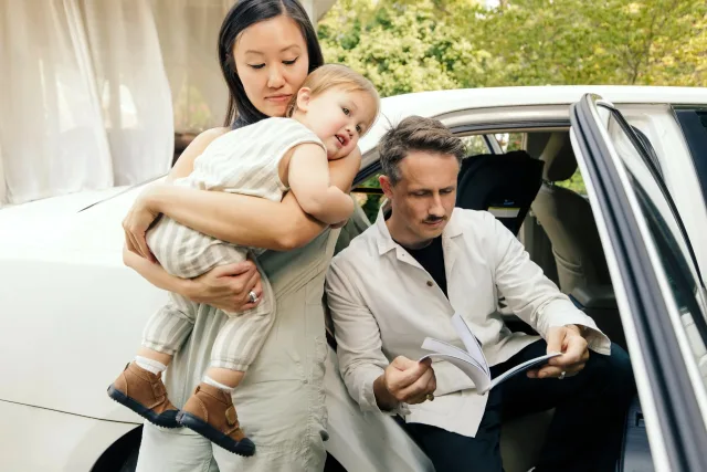 A man and woman holding a baby in a car